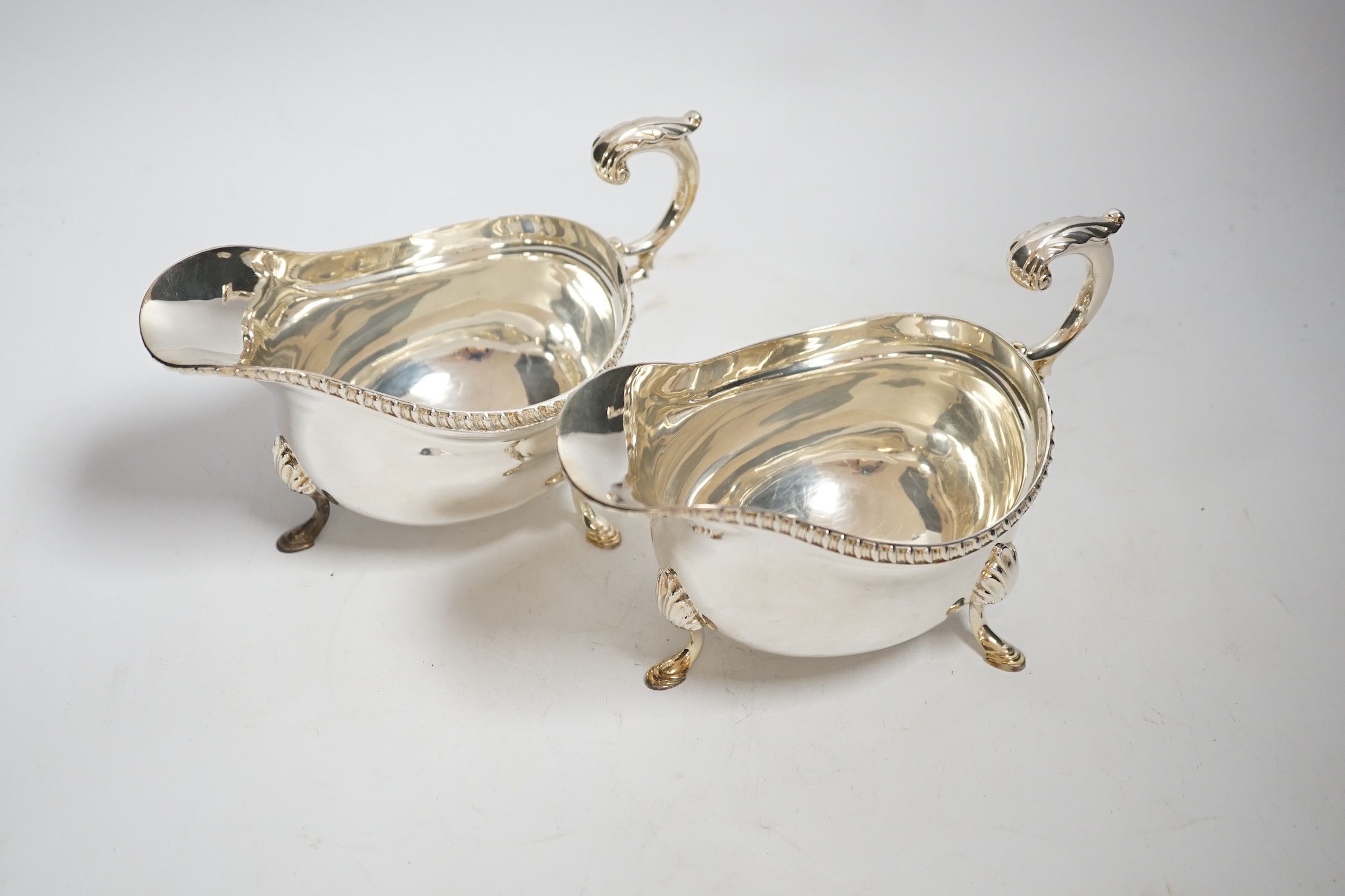 A pair of Elizabeth II silver sauceboats, with flying scroll handles, by Garrard & Co, London, 1961, length 17.9cm, 20oz.